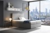 Elegantes graues Boxspringbett in einem modernen Zimmer mit Blick auf die Skyline.