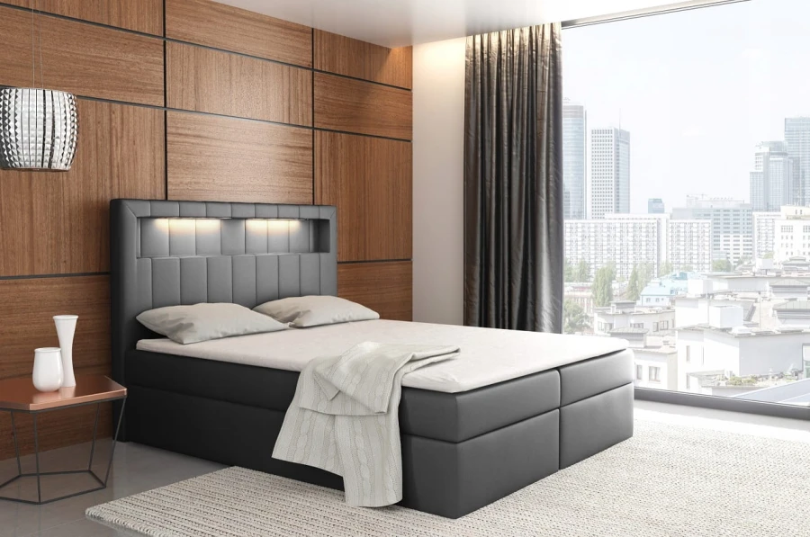 Anthrazitfarbenes Boxspringbett mit LED-Kopfteil und moderner Stadtansicht im Hintergrund.