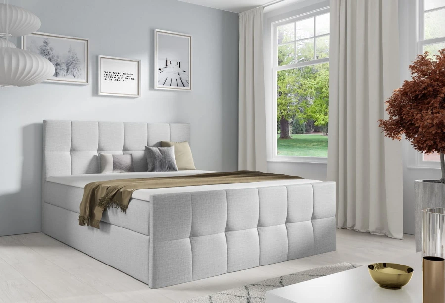 Hellgraues Boxspringbett mit Stoffbezug in hellem, freundlichem Schlafzimmer.