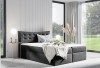 Anthrazitfarbenes Boxspringbett mit gestepptem Samt-Kopfteil und weißer Decke.