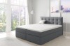 Modernes graues Boxspringbett mit gestepptem Kopfteil in hellem Zimmer.