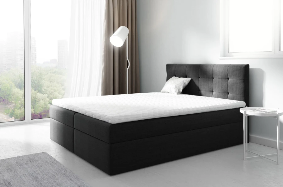 Dunkelgraues Boxspringbett in modernem Design mit weißem Topper und weichem Kopfteil.