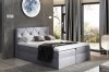 Graues Boxspringbett in modernem Design mit gemütlicher Matratze und dunklen Vorhängen.