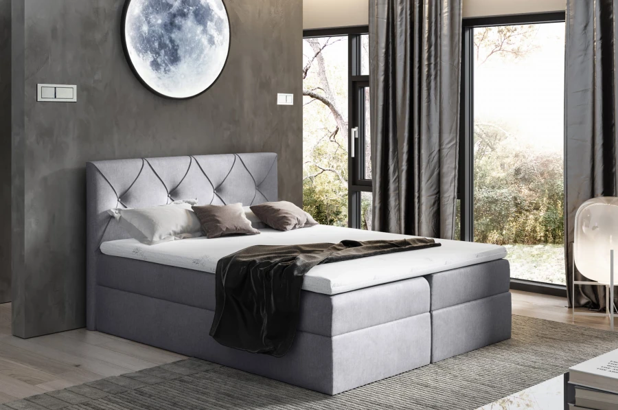 Graues Boxspringbett in modernem Design mit gemütlicher Matratze und dunklen Vorhängen.