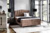 Modernes Boxspringbett in Braun mit elegantem Kopfteil und schwarzen Füßen.