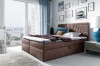Braunes Boxspringbett mit gepolstertem Kopfteil im modernen Schlafzimmer mit Stadtblick.