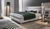 Graues Boxspringbett mit gestepptem Kopfteil in modernem Schlafzimmerambiente.