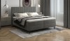 Modernes graues Boxspringbett mit hohem Kopfteil und gemütlicher Bettwäsche im Schlafzimmer.