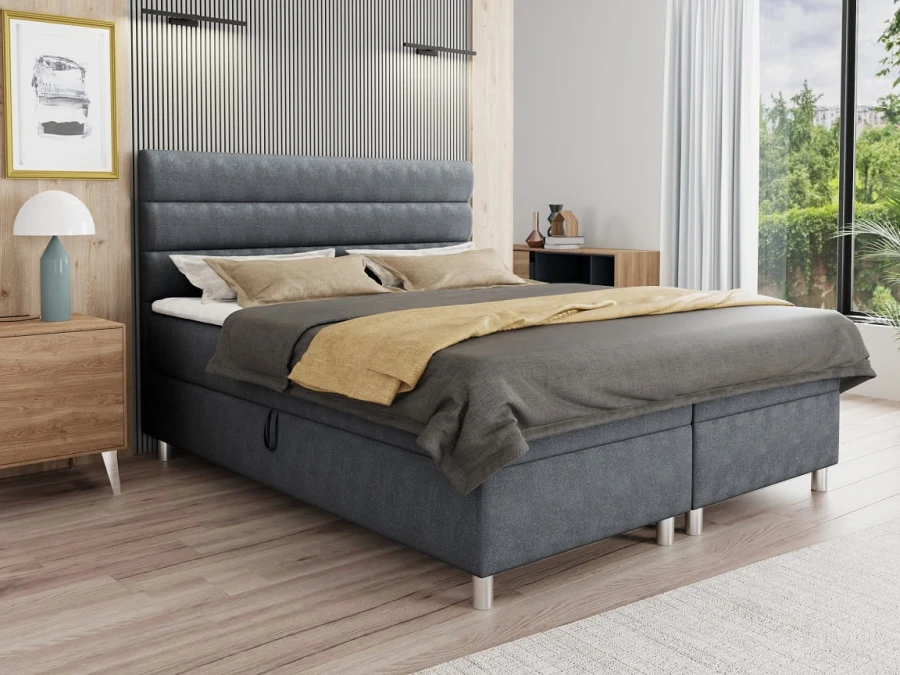Modernes graues Boxspringbett mit horizontal gestepptem Kopfteil in hellem Schlafzimmerambiente.