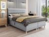 Graues Boxspringbett mit gepolstertem Kopfteil und Stauraum im Schlafzimmer.