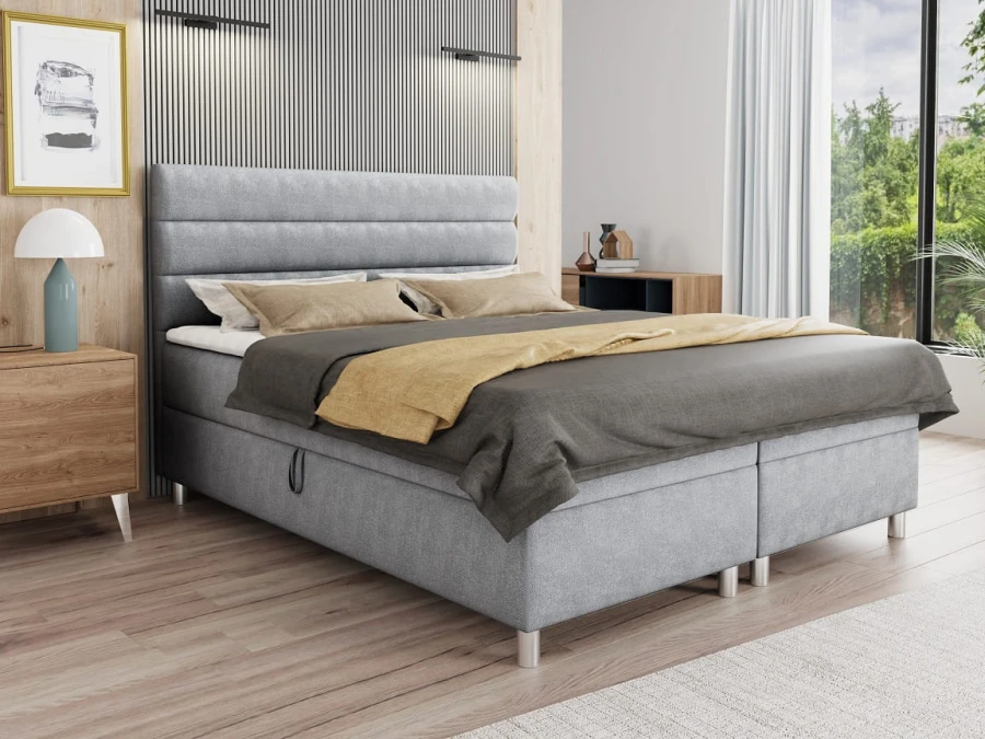 Graues Boxspringbett mit gepolstertem Kopfteil und Stauraum im Schlafzimmer.
