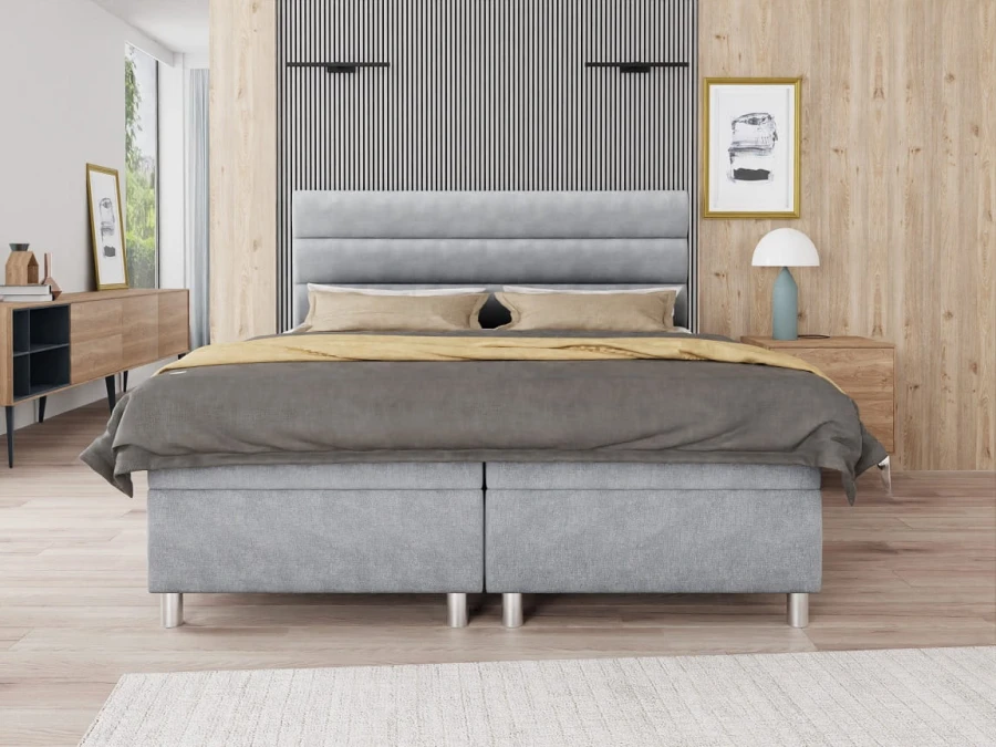 Frontale Ansicht eines grauen Boxspringbettes in stilvoller Schlafzimmer-Einrichtung.