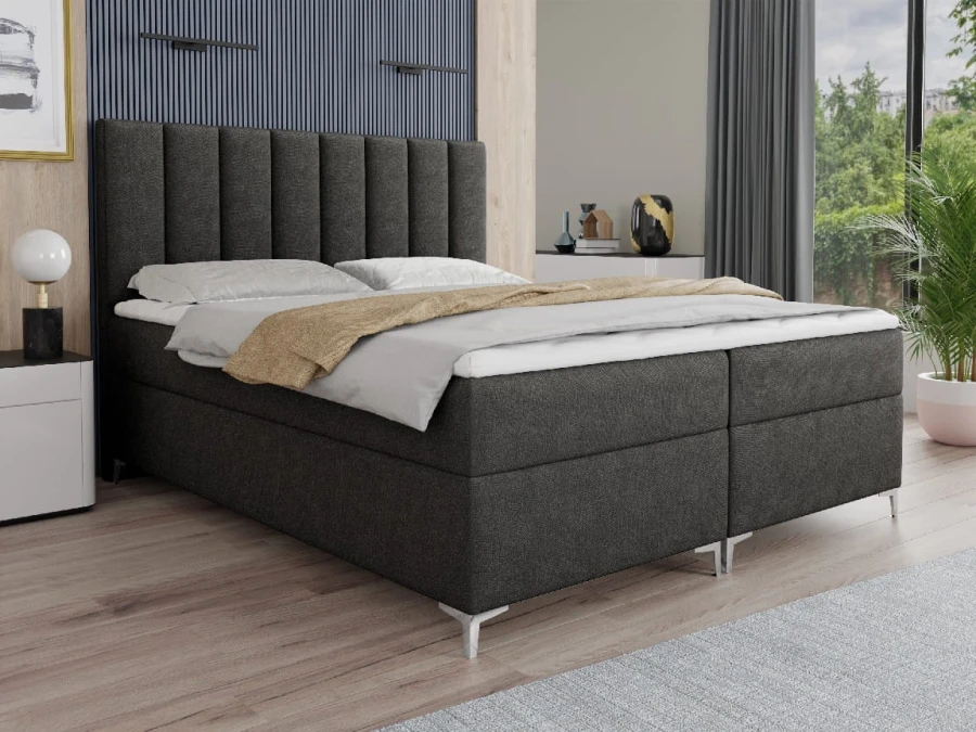Dunkelgraues Boxspringbett mit vertikal gestepptem Kopfteil und eleganten Metallfüßen.