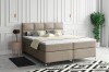 Gemütliches Boxspringbett in Beige mit Kissen in einem hellen Wohnambiente.
