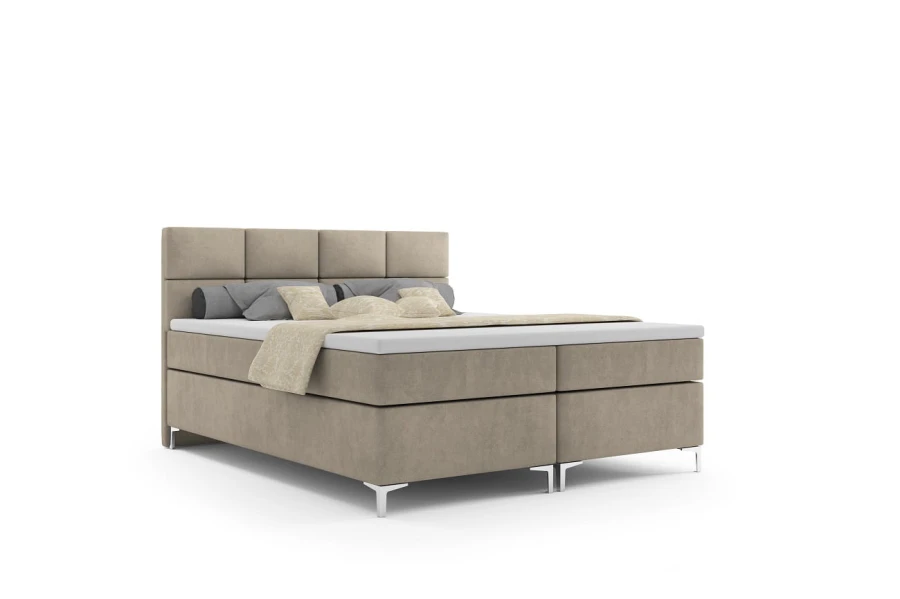 Beiges Boxspringbett mit gestepptem Kopfteil und Kissen, isoliert auf weißem Hintergrund.