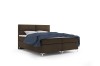 Boxspringbett in Braun mit blauer Decke, freigestellt auf weißem Hintergrund.