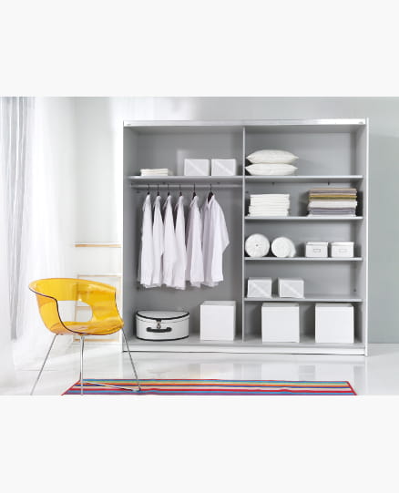 Organisiertes Kleiderschrank-Innenleben mit Hemden auf Bügeln und weißen Aufbewahrungsboxen.