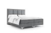 Freigestelltes graues Boxspringbett mit hohem Kopfteil und weißer Bettwäsche.