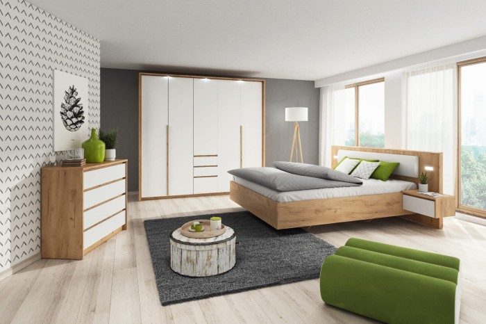 Modernes Schlafzimmer mit Holzbett, großem weißem Kleiderschrank und grünen Farbakzenten.