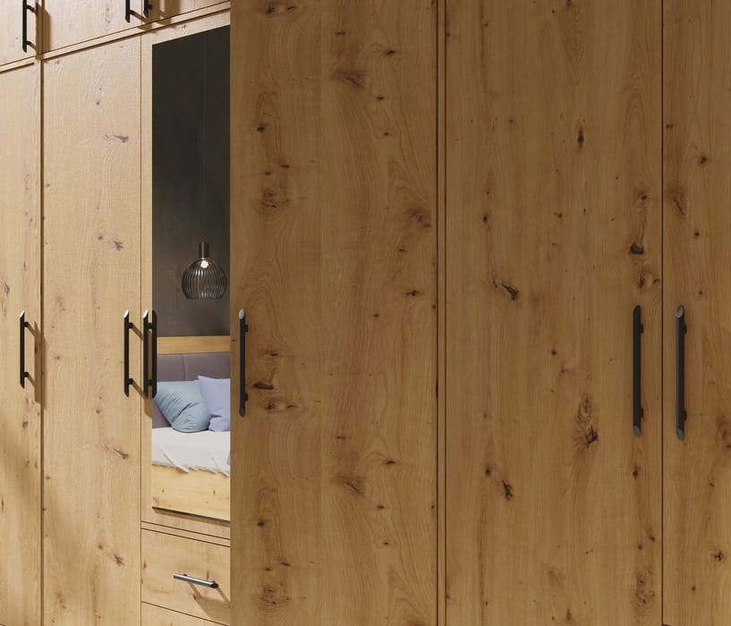Detailansicht der Kleiderschrank-Fronten in Eiche-Optik mit eleganten schwarzen Metallgriffen.