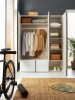 Einblick in einen organisierten Kleiderschrank mit Kleidung, Körben und Schuhen.