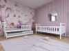 Zwei weiße Kinderbetten in einem hellen Zimmer mit rosa Akzenten.