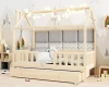 Hausbett aus Naturholz mit Lichterkette und gemütlichen Polstern in einem hellen Kinderzimmer.