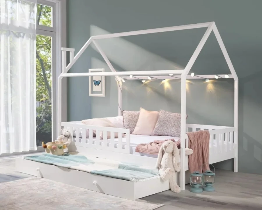 Gemütliches weißes Hausbett mit Lichterkette und ausgezogenem Gästebett im stilvollen Kinderzimmer.