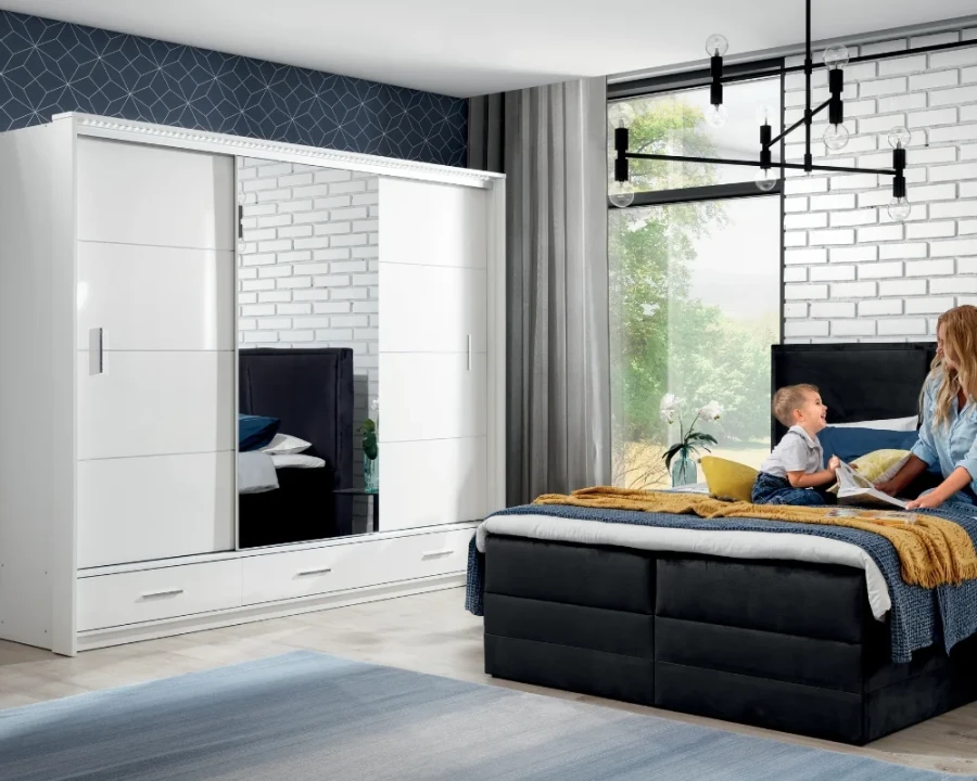 Großer weißer Kleiderschrank mit Schiebetüren und Spiegel in hellem Schlafzimmer.