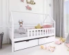 Weißes Kinder-Hausbett aus Holz mit Bettkasten und Rausfallschutz, dekoriert mit Kissen und Spielzeug.