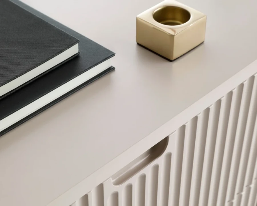 Detailansicht der geriffelten Oberfläche und Griffmulde eines beigen Sideboards.