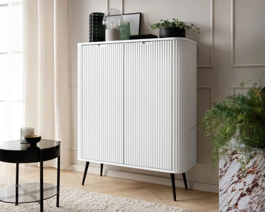 Weißes Highboard mit vertikaler Riffel-Struktur und schwarzen Beinen als modernes Aufbewahrungsmöbel.