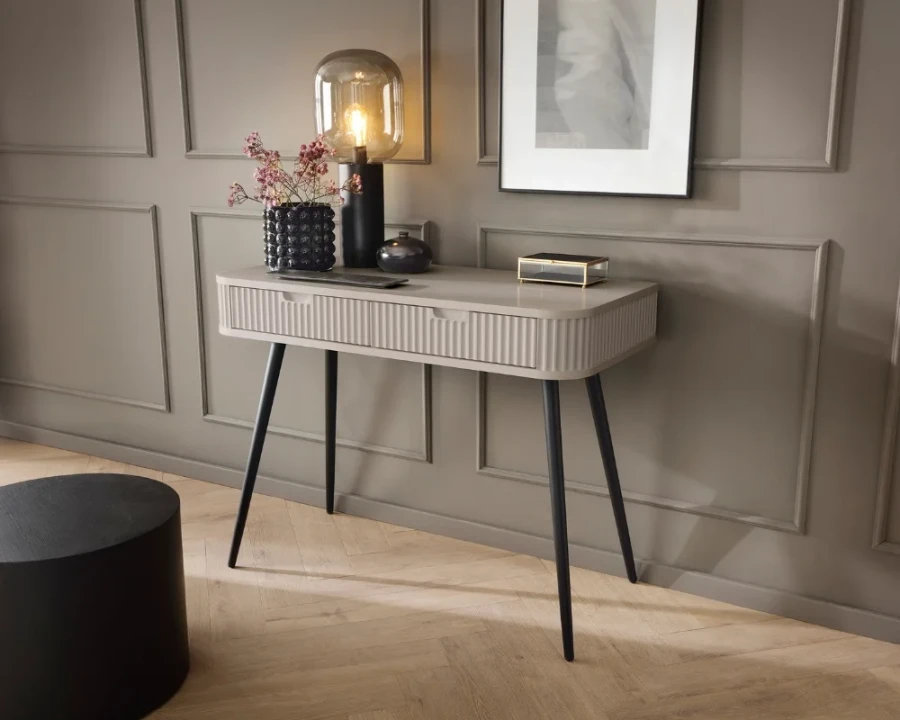 Beige console table with a fluted design in an elegant setting with parquet flooring.