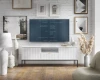 Weißes TV-Lowboard mit geriffelter Front und schwarzen Beinen in einem modern eingerichteten Wohnzimmer.