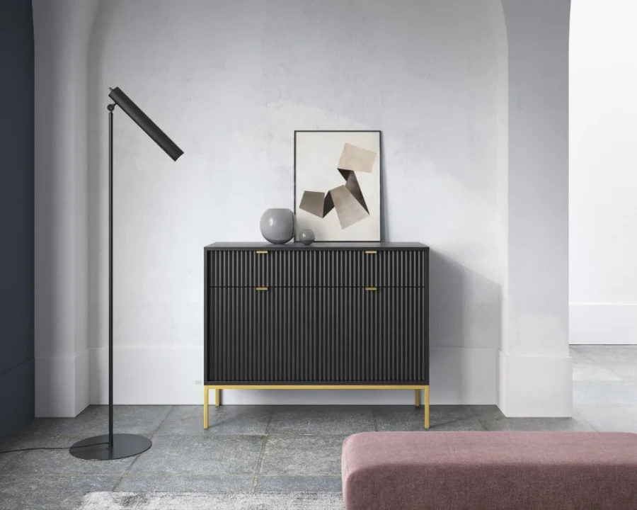 Elegantes Interieur mit schwarzer Kommode auf goldenen Metallbeinen.
