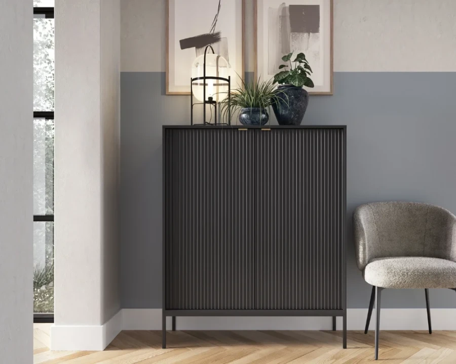Schwarzes Highboard mit vertikalen Rillen und moderner Dekoration im Wohnbereich.