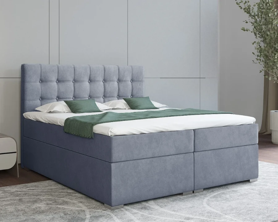Blaues Boxspringbett mit gestepptem Kopfteil und grüner Decke für ein modernes Schlafzimmer.