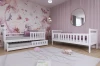 Set aus zwei weißen Kinderbetten, inkl. Ausziehbett, in einem modern gestalteten Mädchenzimmer.