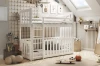 Weißes Etagenbett mit integriertem Gitterbett im Abenteuer-Kinderzimmer mit Spielzeug und Kletternetz.