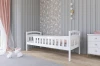 Niedriges weißes Kinderbett aus Holz mit Absturzsicherung im skandinavischen Design.