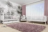 Weißes Kinderbett aus Holz im modern gestalteten Kinderzimmer mit Dschungel-Tapete und rosa Teppich.