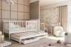 Weißes Kinderbett mit Ausziehbett und Schubladen im hellen Kinderzimmer.