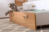 Geöffnete Bettschublade aus Holz mit Plüschhase als praktischer Stauraum im Kinderzimmer.