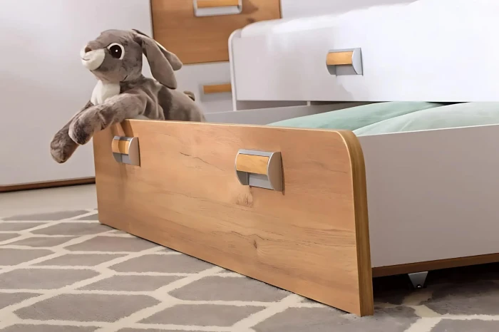 Geöffnete Bettschublade aus Holz mit Plüschhase als praktischer Stauraum im Kinderzimmer.