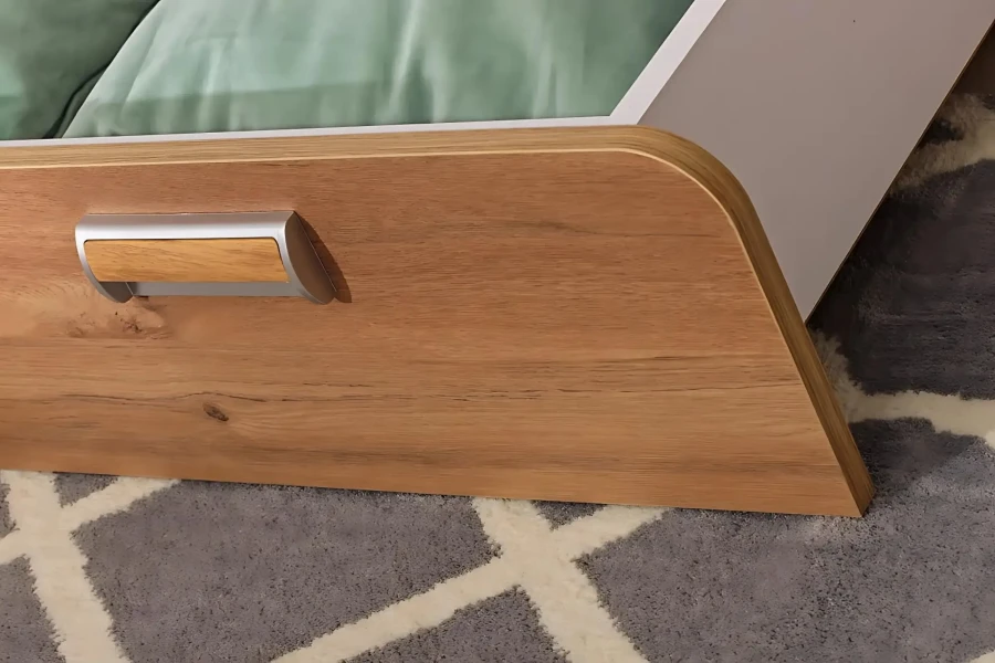 Nahaufnahme einer Bettschublade in Holzoptik mit modernem Metallgriff für Jugendbetten.