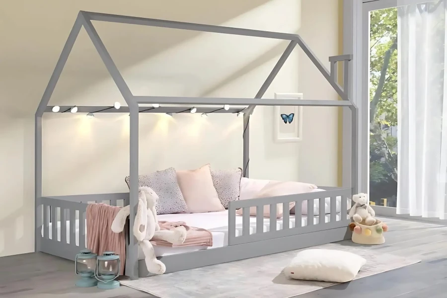 Gemütliches Kinderhausbett in Grau mit Lichterkette, Kuscheltieren und weichen Kissen dekoriert.
