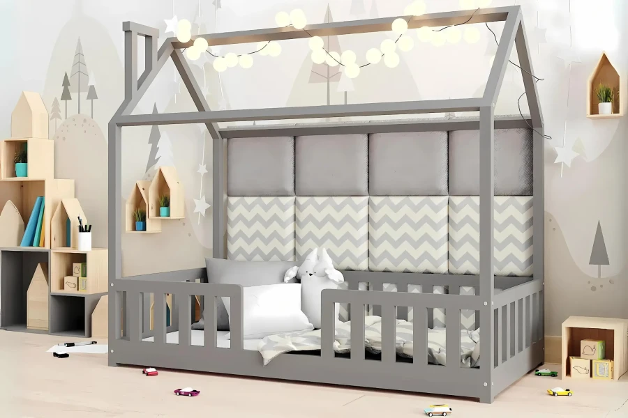 Graues Kinderhausbett mit gepolstertem Kopfteil und dekorativer Lichterkette.