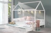 Gemütliches weißes Kinderbett in Hausform mit Beleuchtung und Kissen in einem hellen, modernen Raum.