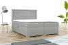 Modernes graues Boxspringbett mit strukturiertem Kopfteil in hellem Schlafzimmer-Ambiente.
