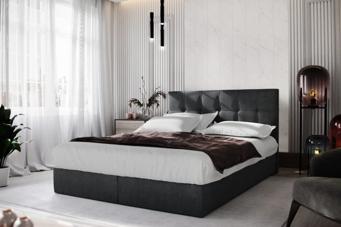 Modernes dunkelgraues Boxspringbett mit gestepptem Kopfteil in hellem Schlafzimmer.